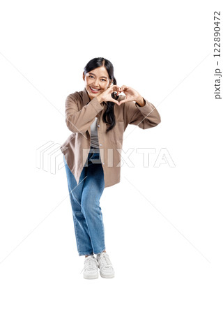 Portrait of an Asian Indonesian Woman in a shirt with a happy expression showing a heart shape gesture isolated over a white background 122890472