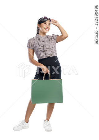 Portrait of an Asian Indonesian woman with sunglasses carrying a shopping bag isolated over a white background. Copy space or mockup. Concept of shopping, lifestyle, or consumerism 122890496