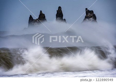 Panoramic view of ocean waves with protruding rocks from black sand beach Reynisfjara, Iceland. Nature, travel, winter background, or wallpaper Panoramic view of ocean waves with protruding rocks from black sand beach Reynisfjara, Iceland. Nature, travel, winter background, or wallpaper 122890549