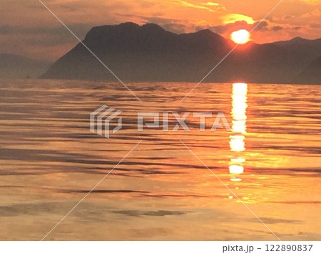 沈む夕日と山のシルエット 122890837