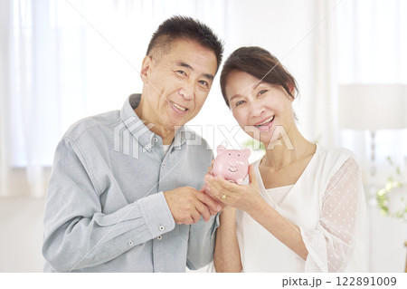 貯金箱を持つシニア夫婦 リビング 貯金箱を持つシニア夫婦 リビング 122891009