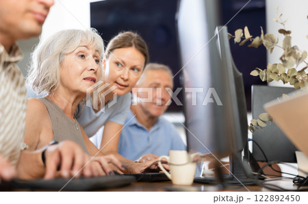 Old woman learning computer programs with teacher in training room Old woman learning computer programs with teacher in training room 122892450