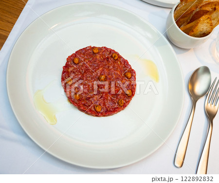 Exquisite French dish is veal tartare decorated with pickled capers 122892832
