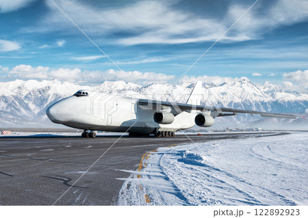 White wide body transport cargo airplane at winter airport on the background of high scenic mountains 122892923
