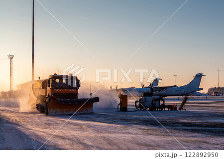 Snowplow truck cleans airport apron in the morning at winter Snowplow truck cleans airport apron in the morning at winter 122892950