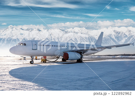 White passenger airliner on the airport apron at winter on the background of high picturesque mountains 122892962