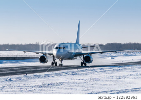 White passenger airliner taxiing on taxiway in snowy winter day 122892963