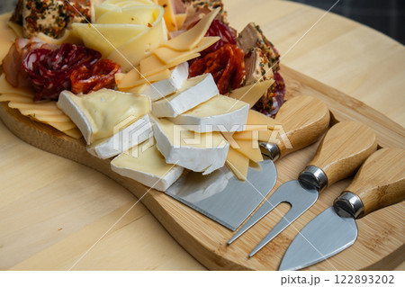 Food trend gift aperitivo party idea. Appetizers wooden grazing board with different antipasti charcuterie snacks and cheese. Assorted cheese meat platter. Disordered eating 122893202