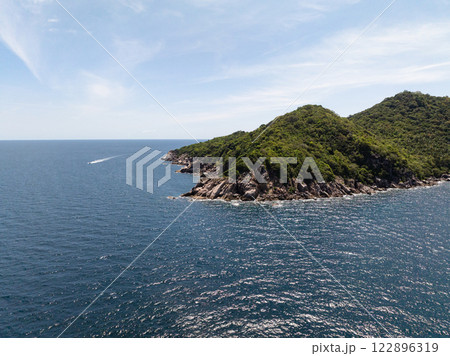 Rocky coastline and lush green hills meeting the vibrant blue sea under a bright clear sky. Koh Tao, Thailand. 122896319