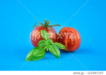 Cherry tomatoes with basil leaves over a blue 122897147