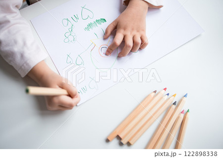 Child drawing with colored pencils on white paper Child drawing with colored pencils on white paper 122898338