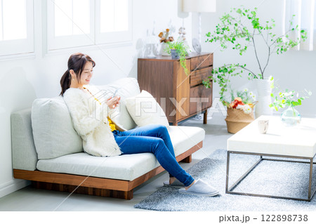 ソファに座ってスマホを見る女性 122898738
