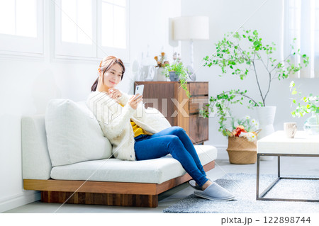 ソファに座ってスマホを見る女性 122898744