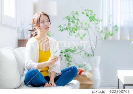 ソファに座ってスマホを見る女性 122898762