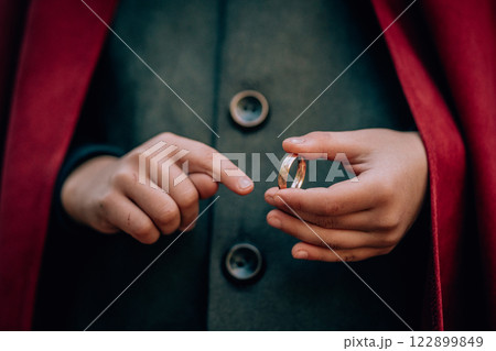 Hands of boy cosplayer in hobbit cape costume holding and wants to wear golden ring. Fantasy journey Hands of boy cosplayer in hobbit cape costume holding and wants to wear golden ring. Fantasy journey 122899849