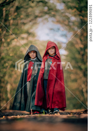 Hobbits boys in cape costumes standing in autumn forest with ring. Fantasy journey, halloween 122899891