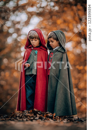 Hobbits boys in cape costumes standing in autumn forest with ring. Fantasy journey, halloween 122899894