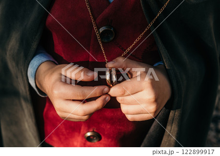 Unrecognizable child cosplayer in hobbit cape costume holding and wants to wear golden ring. Fantasy 122899917
