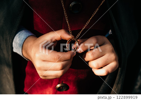 Unrecognizable child cosplayer in hobbit cape costume holding and wants to wear golden ring. Fantasy 122899919