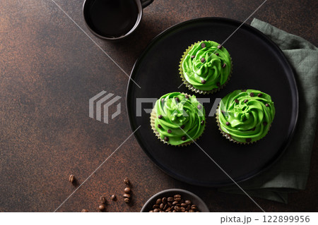 Homemade chocolate cupcakes with coffee and chocolate sprinkles on brown background. St. Patrick's Day. Copy space. View from above. Homemade chocolate cupcakes with coffee and chocolate sprinkles on brown background. St. Patrick's Day. Copy space. View from above. 122899956