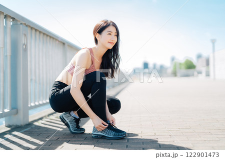 靴紐を結ぶスポーツウェアの女性 122901473