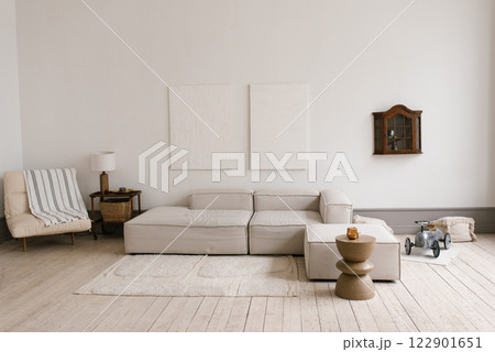 Scandinavian modern minimalistic living room with grey couch and armchair. Small table with lamp and toy car is on the floor Scandinavian modern minimalistic living room with grey couch and armchair. Small table with lamp and toy car is on the floor 122901651