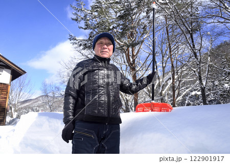 雪国で雪はねを使用して除雪をしている笑顔の老人 雪国で雪はねを使用して除雪をしている笑顔の老人 122901917