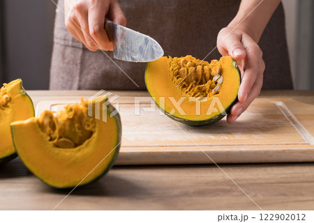 Hand holding kitchen knife and cutting green pumpkin on wooden board, Homemade cooking Hand holding kitchen knife and cutting green pumpkin on wooden board, Homemade cooking 122902012
