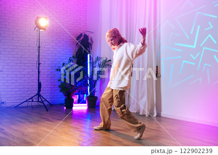 Dancer showcasing dynamic movement in colorful studio with soft lighting and modern decor Dancer showcasing dynamic movement in colorful studio with soft lighting and modern decor 122902239