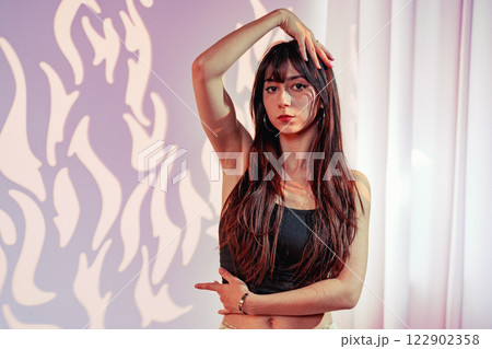 Model poses elegantly in a stylish studio with creative lighting and artistic backdrop 122902358
