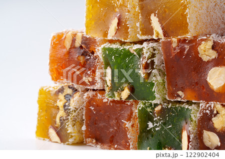 Colorful Turkish delight squares stacked with nuts and coconut flakes on a light background Colorful Turkish delight squares stacked with nuts and coconut flakes on a light background 122902404