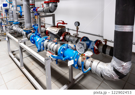 Industrial piping system showing blue and gray pipes and measuring instruments in a modern facility Industrial piping system showing blue and gray pipes and measuring instruments in a modern facility 122902453