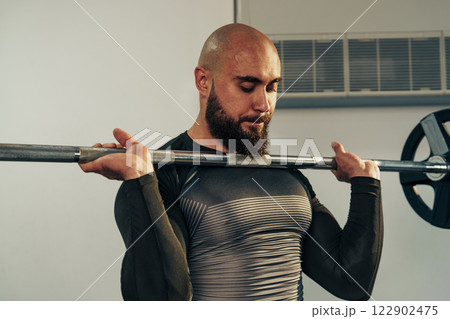 Strong man lifting barbell in a gym during strength training session to build muscle and improve fitness 122902475