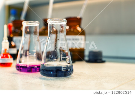 Glass containers with colored liquids on laboratory countertop during scientific experiment in modern facility Glass containers with colored liquids on laboratory countertop during scientific experiment in modern facility 122902514