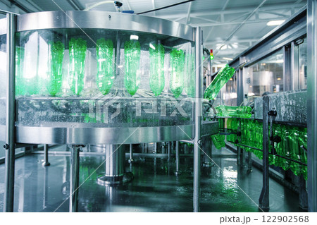 Bottling process in a modern production facility featuring green glass bottles and machinery at work 122902568