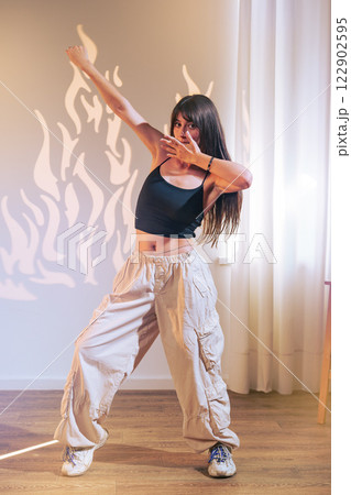 Dancer showcases impressive moves in casual attire with playful shadows in studio setting 122902595
