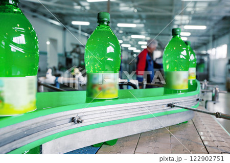 Bottling process of soft drinks in a factory during daytime with green plastic bottles on a conveyor belt 122902751