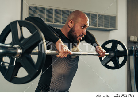 Intense weightlifting session in a modern gym focusing on strength training techniques Intense weightlifting session in a modern gym focusing on strength training techniques 122902768