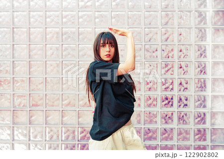 Dancer performing expressive movements against a textured glass wall in an urban setting Dancer performing expressive movements against a textured glass wall in an urban setting 122902802