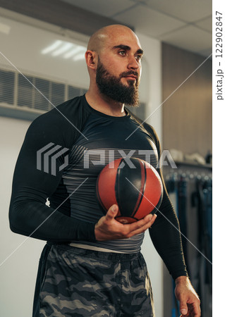 Determined athlete prepares for basketball training in a modern gym setting during the afternoon Determined athlete prepares for basketball training in a modern gym setting during the afternoon 122902847
