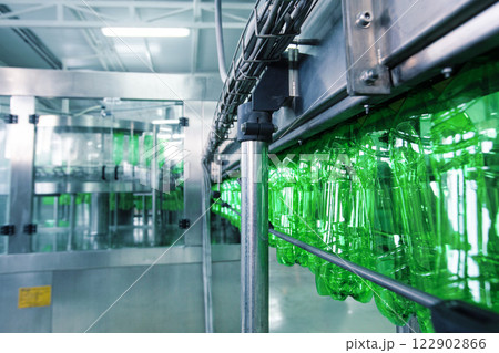 Green plastic bottles moving along a production line in a factory setting during daylight hours 122902866