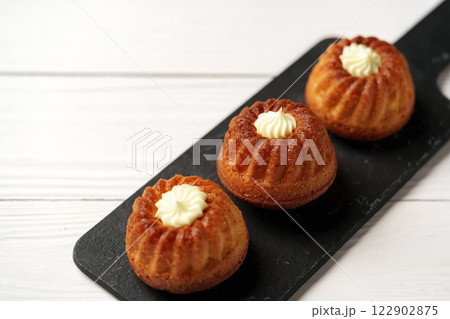 Delicious mini bundt cakes topped with cream on a serving platter in a cozy kitchen setting 122902875