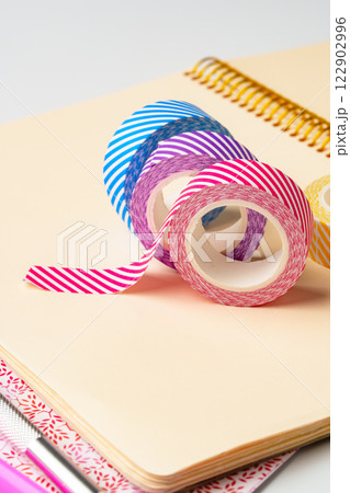 Colorful washi tape rolls arranged on a notepad with a spiral binding for crafting and decoration purposes 122902996