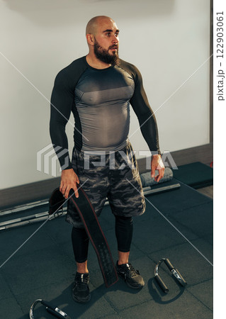 Strong man engages in workout at gym focusing on strength training and fitness routine 122903061