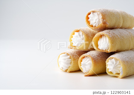 Delicious cream-filled pastries stacked on a white surface ready to be enjoyed at a dessert table Delicious cream-filled pastries stacked on a white surface ready to be enjoyed at a dessert table 122903141