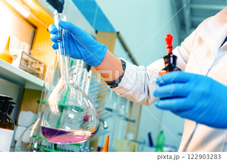 Researcher conducts chemical experiment with flask and reagent in laboratory setting Researcher conducts chemical experiment with flask and reagent in laboratory setting 122903283