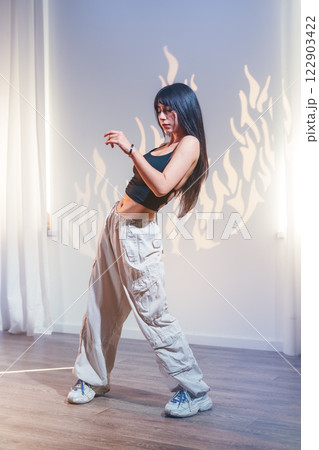 Young woman dances gracefully in a studio with artistic fire shadow on the wall 122903422
