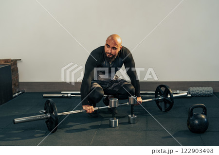 Fitness enthusiast engaged in strength training with weights in a gym setting during the evening 122903498