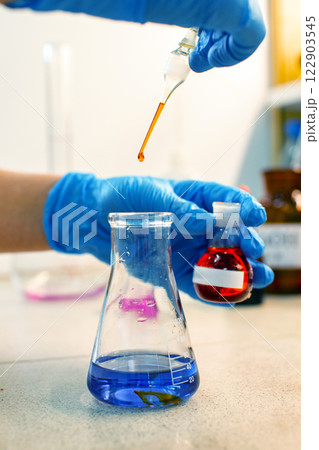Chemistry experiment involves mixing colored liquids in laboratory setting with precise droplet measurements 122903545