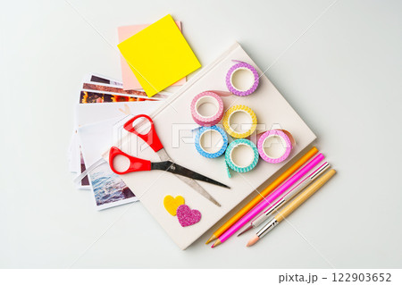 Crafting supplies arranged on a white table with scissors, washi tape, and colored pencils for creative projects Crafting supplies arranged on a white table with scissors, washi tape, and colored pencils for creative projects 122903652